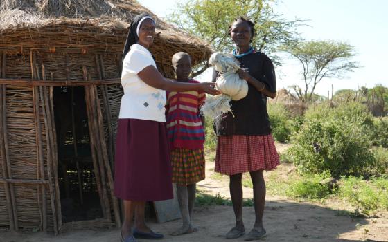 Sr. Jannifer Hiuhu hands over food rations to Chepokoronto Lotingora, a 33-year-old mother of eight. After a fire destroyed Lotingora's former home and claimed two of her children, the Incarnate Word Sisters helped her rebuild her home and provided her with food to sustain her family. (GSR photo/Wycliff Peter Oundo)