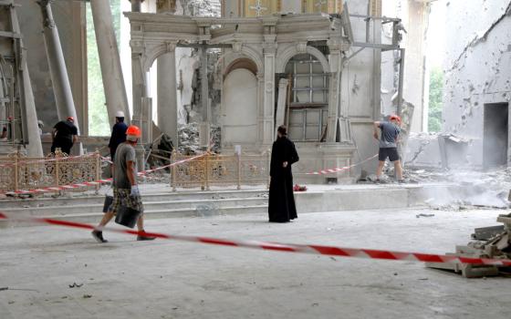 A person in all black and a construction worker stand in a crumbling cathedral