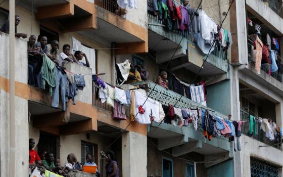 Many people gather on apartment balconies where clotheslines full of clothes also hang