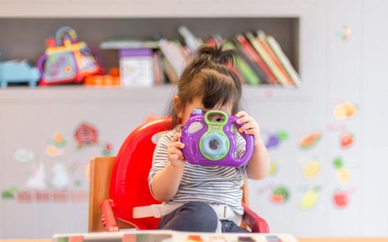 Little girl with toy camera covering her face