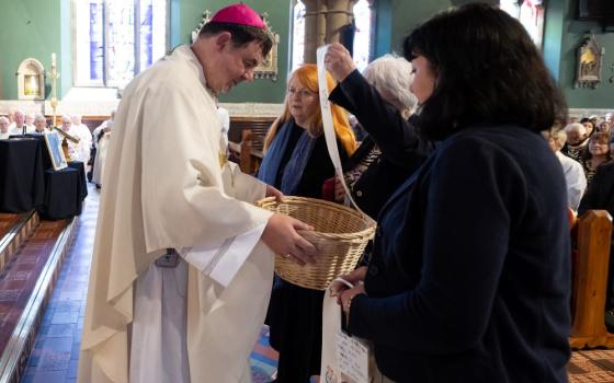 Bishop Stephen Wright, the new leader of the Hexham and Newcastle Diocese, accepts prayer ribbons representing victims of abuse during his installation service July 19.