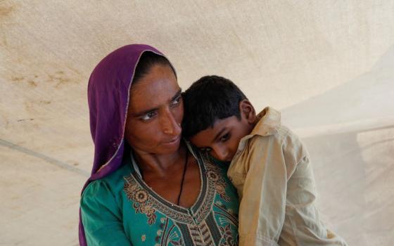 A woman who became displaced following rains and floods during the monsoon season holds her child while standing outside her tent in Sehwan, Pakistan, Sept. 13, 2022. (OSV News/Reuters/Akhtar Soomro)