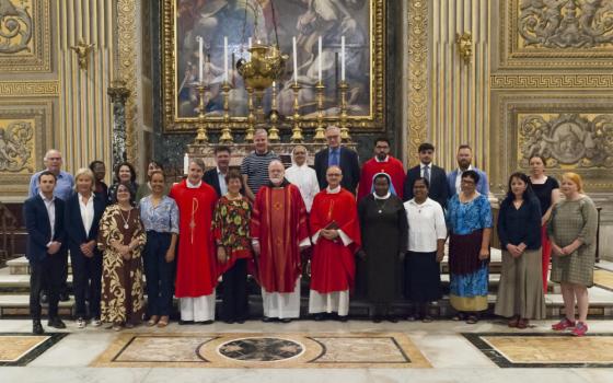 A group of people including prelates, sisters and lay people pose for a picture in an ornately decorated space