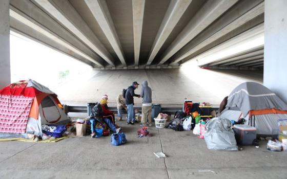 Homeless men in 2019 are seen outside their tents under a bridge in Austin, Texas. 