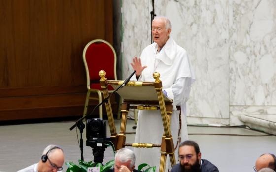 Dominican Fr. Timothy Radcliffe stands at lectern and speaks into mic.