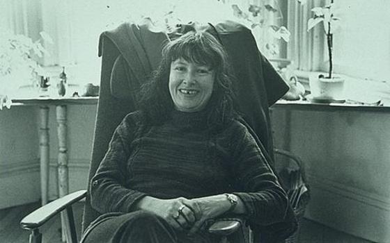 Denise Levertov sits in a chair in front of a window.