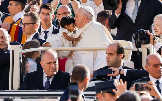 Pope Francis greets a child as he rides in the popemobile around St. Peter’s Square at the Vatican before his weekly general audience Oct. 11. (CNS/Lola Gomez)