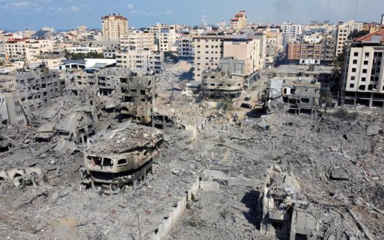 Rubble surrounds the remains of burned out concrete buildings which are seen from an aerial photograph