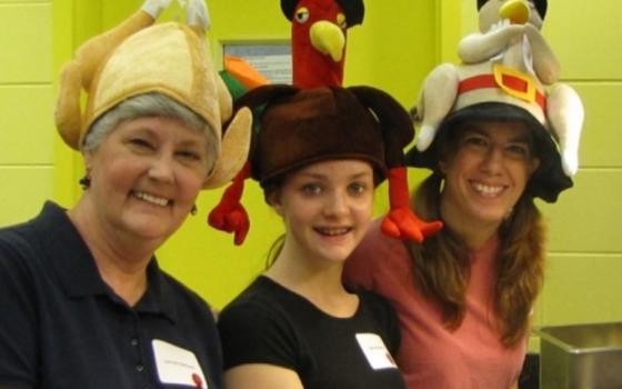 Three women wear hats that look like turkeys.