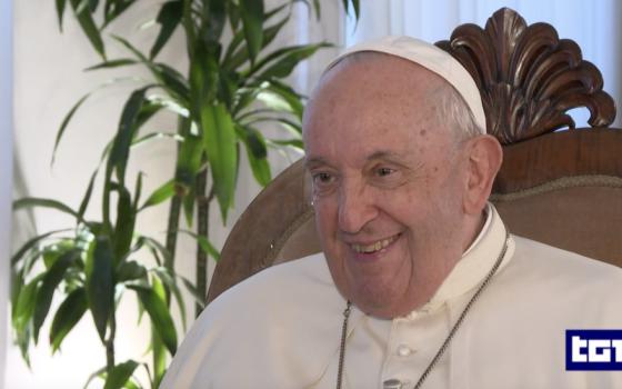 Pope Francis sits in a chair and smiles. A TG1 logo is at the bottom right of the screen.