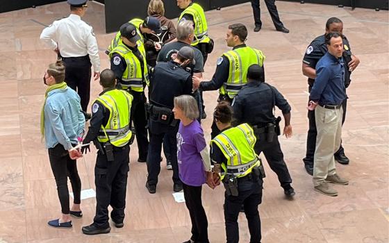 U.S. Capitol Police officers arrest several Catholic activists during a witness inside the Hart Senate Office Building on Nov. 9 to call for an Israel-Hamas cease-fire. At bottom, in purple, is Jean Stokan, justice coordinator for immigration and nonviolence for the Sisters of Mercy of the Americas. At right, in blue button-down shirt, is Eli McCarthy, just peace fellow for the Franciscan Action Network. (NCR photo/Joshua J. McElwee)