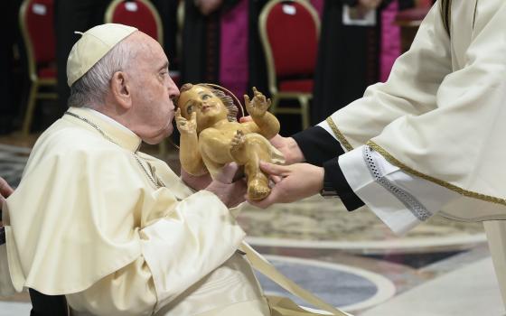 Pope Francis kisses a figurine of the baby Jesus during Christmas Eve Mass in St. Peter's Basilica at the Vatican Dec. 24, 2022. (CNS photo/Vatican Media)