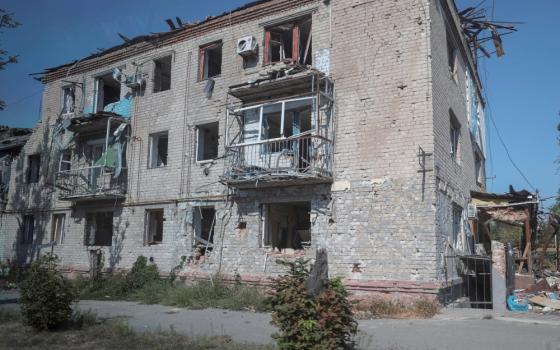 A three-story building is visible without windows and a clearly damaged roof and balconies