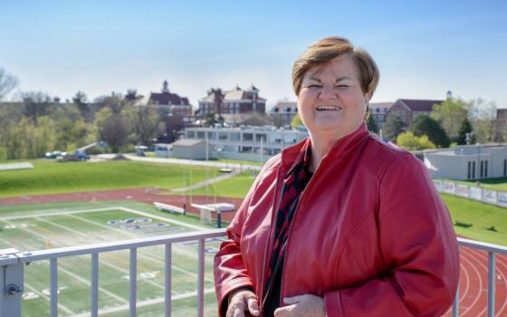 Sr. Peg Albert stands in box at college stadium.