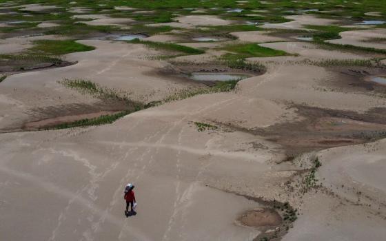 A resident of a riverside community carries food and containers of drinking water distributed due to the drought in Careiro da Varzea, Amazonas state, Brazil, Oct. 24.