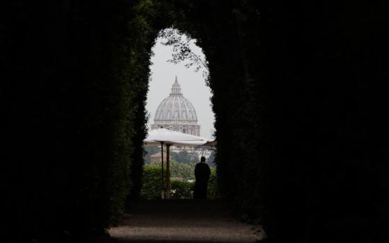 The dome of St. Peter's Basilica is visible through an arched window in a stone wall