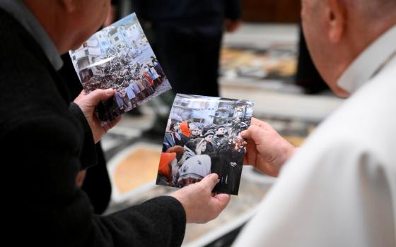 Pope Francis looks at photos of the aftermath of a massive landslide in October 1963 that killed 1,910 people in northern Italy during an audience with pilgrims from the Diocese of Belluno-Feltre and from the association "Vajont: The Future of Memory," and local government officials in the Apostolic Palace at the Vatican Jan. 19, 2024. (CNS photo/Vatican Media)