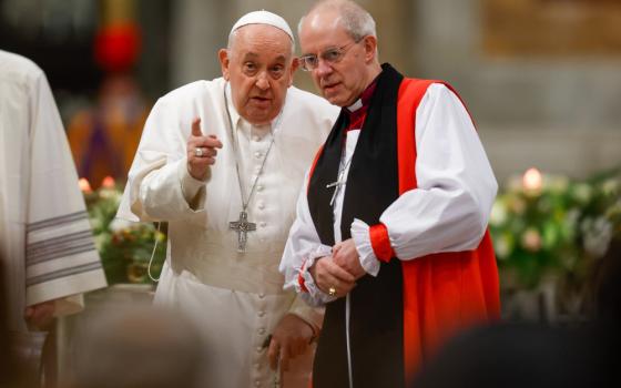 Pope Francis leans towards Archbishop Welby while speaking and pointing