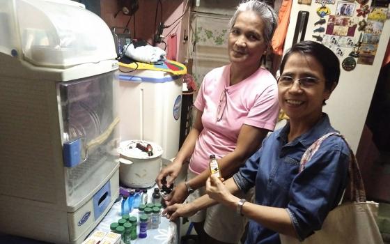 Francia, left, and Sister Arabella look at bottles of pain relievers, part of Francia's income-generating project on Sept. 2, 2023. Francia's house in Paco, Manila, Philippines, accommodates only two people. (Jerahmeel Cruz)