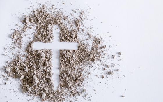 Cross traced in a pile of ash on a white surface (Dreamstime/Thai Noipho)