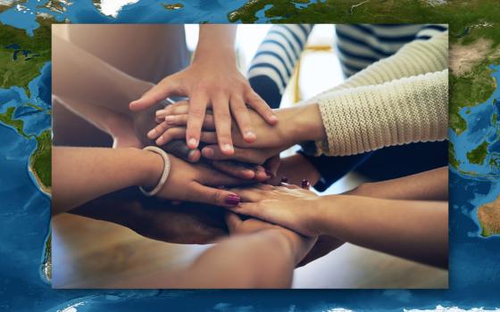 Hands joining in support overlaid on satellite image map of the Earth (Dreamstime/Yuri Arcurs/Scalinger)