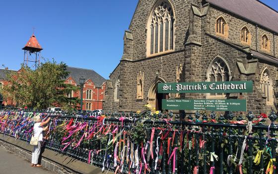 A woman puts a ribbon on the fence of St. Patrick's Cathedral in Ballarat, Australia, Feb. 27, 2019. The ribbons raise awareness and show support for victims of abuse. (CNS/Reuters/Jonathan Barrett)