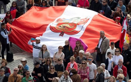 Visitors hold up a flag from Peru in St. Peter's Square at the Vatican March 26, 2023. According to Vatican police, some 35,000 people gathered in the square to join Pope Francis in praying the Angelus. (CNS photo/Vatican Media)