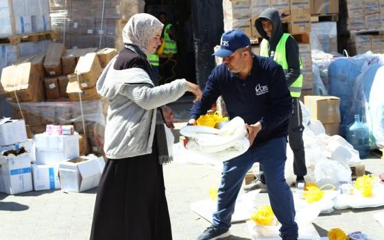 Aid worker hands item to woman