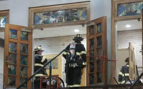 Firefighters seen through open doors of church. 