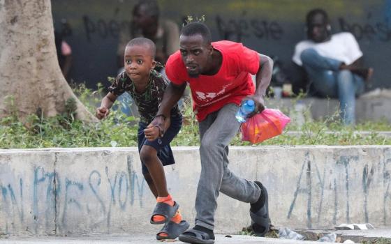 A man and young boy duck and run through street.