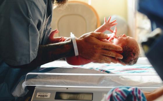 Person holds baby in hospital ward. 