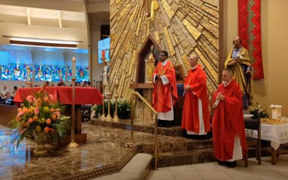 Priest, vested, stands before altar