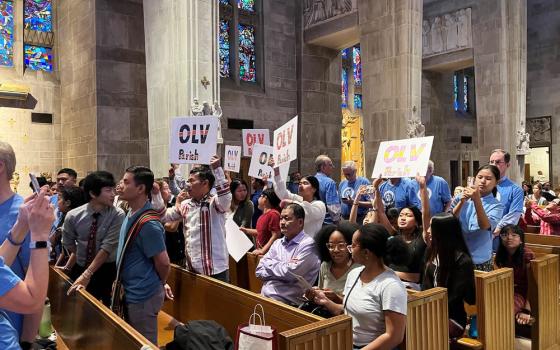 Community attendees wave flags during a community forum at Cathedral of Mary Our Queen in the Archdiocese of Baltimore April 30.