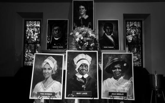 Black and white photo of the banners of the "Saintly Six" displayed in a church. 