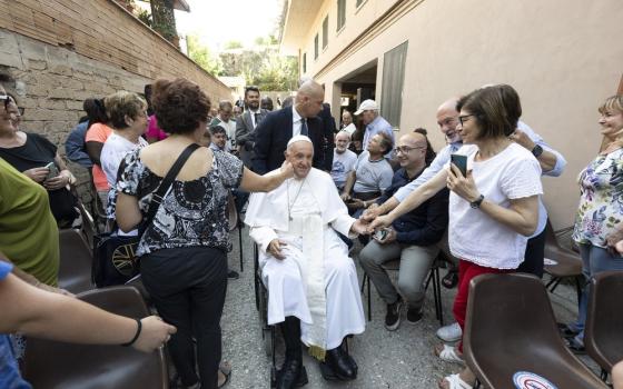 Pope Francis, in a wheelchair, is caressed by devotees. 