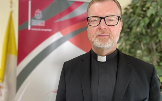 Father Zollner poses in front of an event banner. 