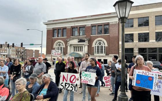 People stand on street holding signs in opposition to bill