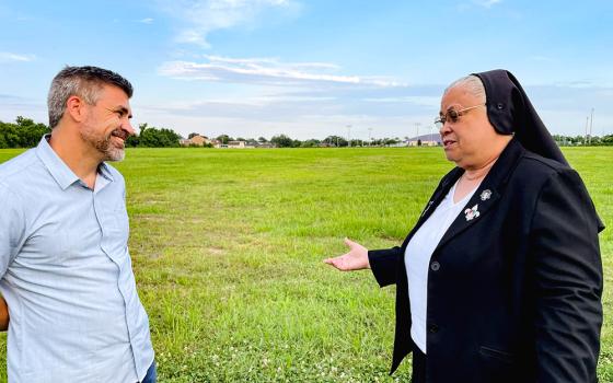 Broderick Bagert, a Together New Orleans organizer, listens to Sr. Alicia Costa, superior of the Sisters of the Holy Family, with the sisters' land designated for the solar field in the background. In the far background is St. Mary's Academy. (Kevin Fitzpatrick)