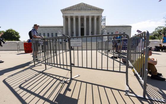 People sit and stand in front of large courthouse building