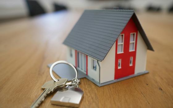 A set of keys on a table next to a toy house (Unsplash/Tierra Mallorca)