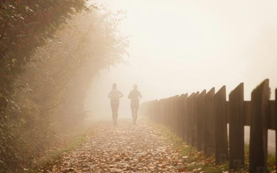 Two people walk outside in a rustic fall setting, moving toward a foggy horizon.(Unsplash/Greg Rosenke)