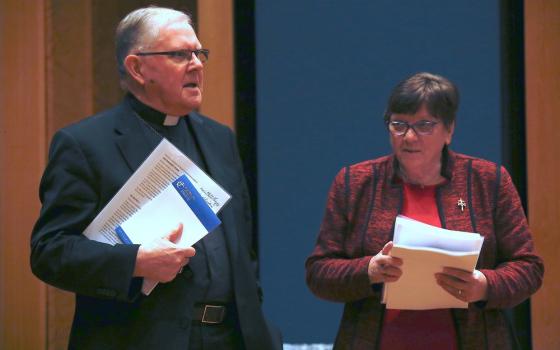 Coleridge and Cavanagh both standing, holding presentation materials. 