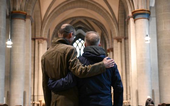 Two men pictured from behind with arms on each other's shoulder. 