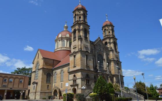 Large, stone Church building pictured from below, looming against bright blue sky. 