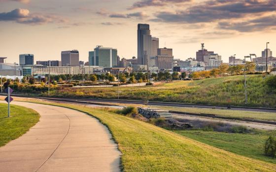 Skyline at dusk show in distance, long green-lined path foregrounded. 