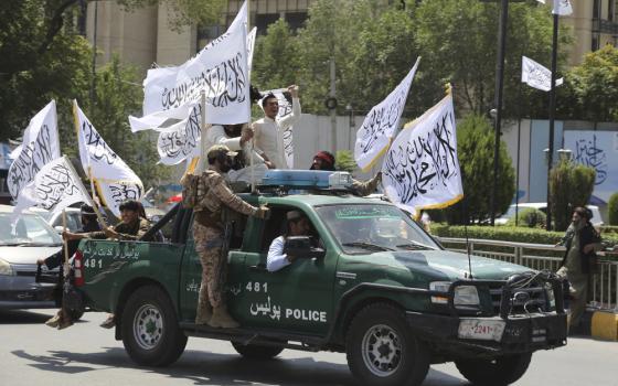 Soldiers ride in truck holding flags. 