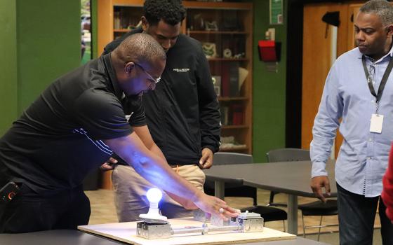 Kelly Stokes, far left, an instructor with Electricians Local 1 in St. Louis, works with student Roderick Brown from St. Mary's South Side Catholic High School in St. Louis, while Tracy Hykes, a pre-apprentice instructor, at right, looks on. (Courtesy of St. Mary’s South Side Catholic High School)