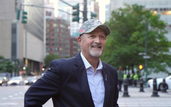 Siller stands in New York City, wearing a suit jacket and ballcap. 