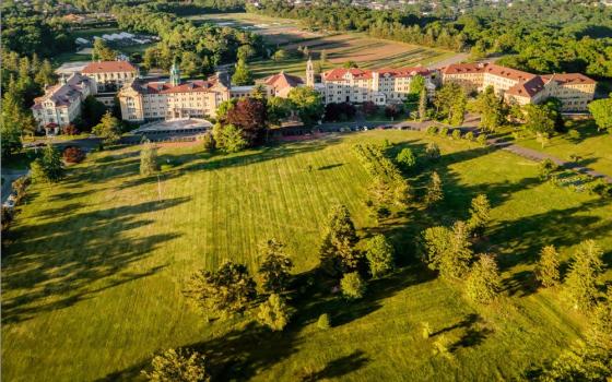 Large complex sitting on sprawling, green lawn seen from above.