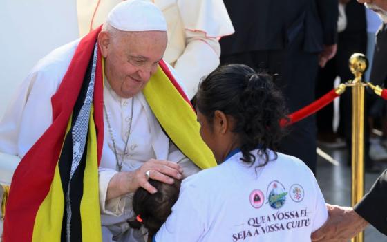 Pope Francis greets a woman and child during an outdoor Mass in Tasitolu, East Timor, Sept. 10. The first to greet him upon his arrival to the country were the tarmac workers. (CNS/Vatican Media)